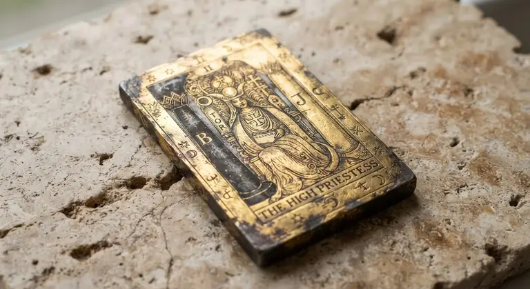 Engraved tarot artifact resting on warm stone